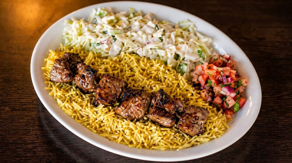 Grilled meat skewers on yellow rice with coleslaw and tomato salsa on a white plate.